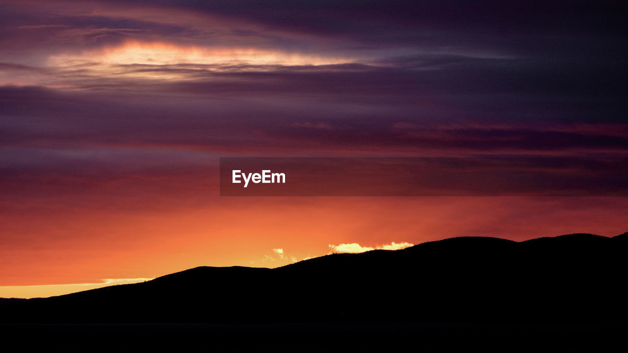 SCENIC VIEW OF SILHOUETTE MOUNTAINS AGAINST ORANGE SKY