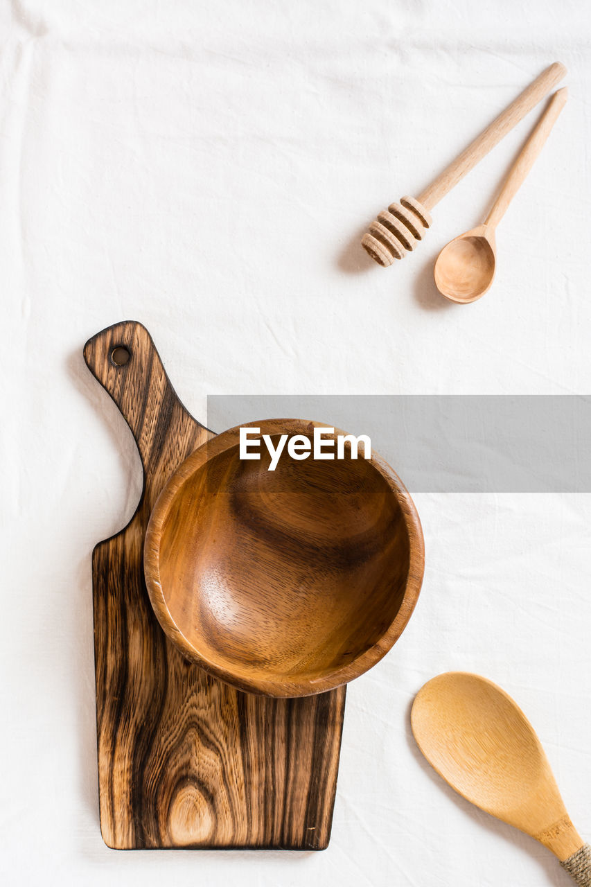 An empty wooden bowl on a cutting board and wooden spoons on a cloth. top and vertical view