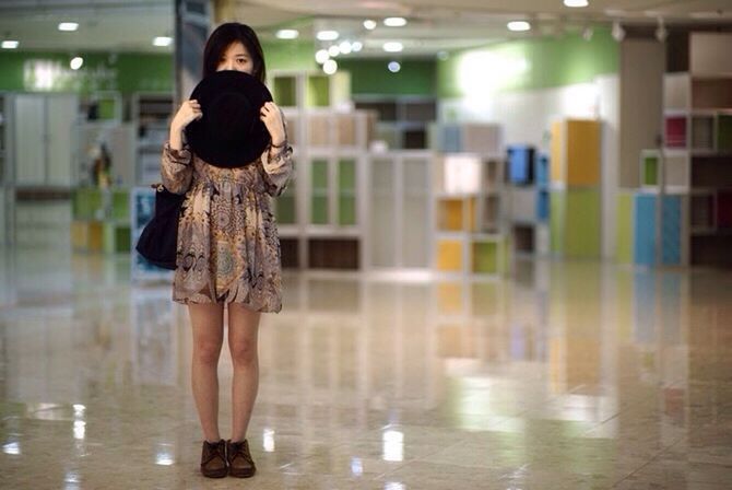 Full length portrait of woman with hat in shopping mall