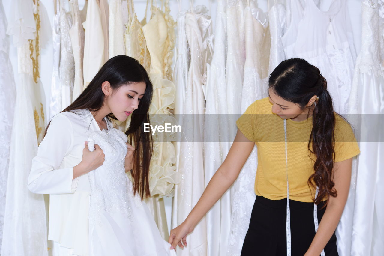 Bride with owner choosing wedding dress at bridal shop