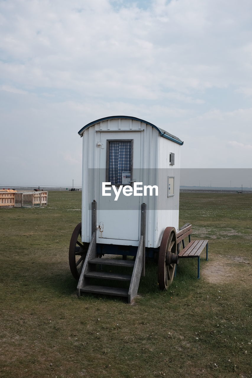 Portable toilet on grassy field against sky