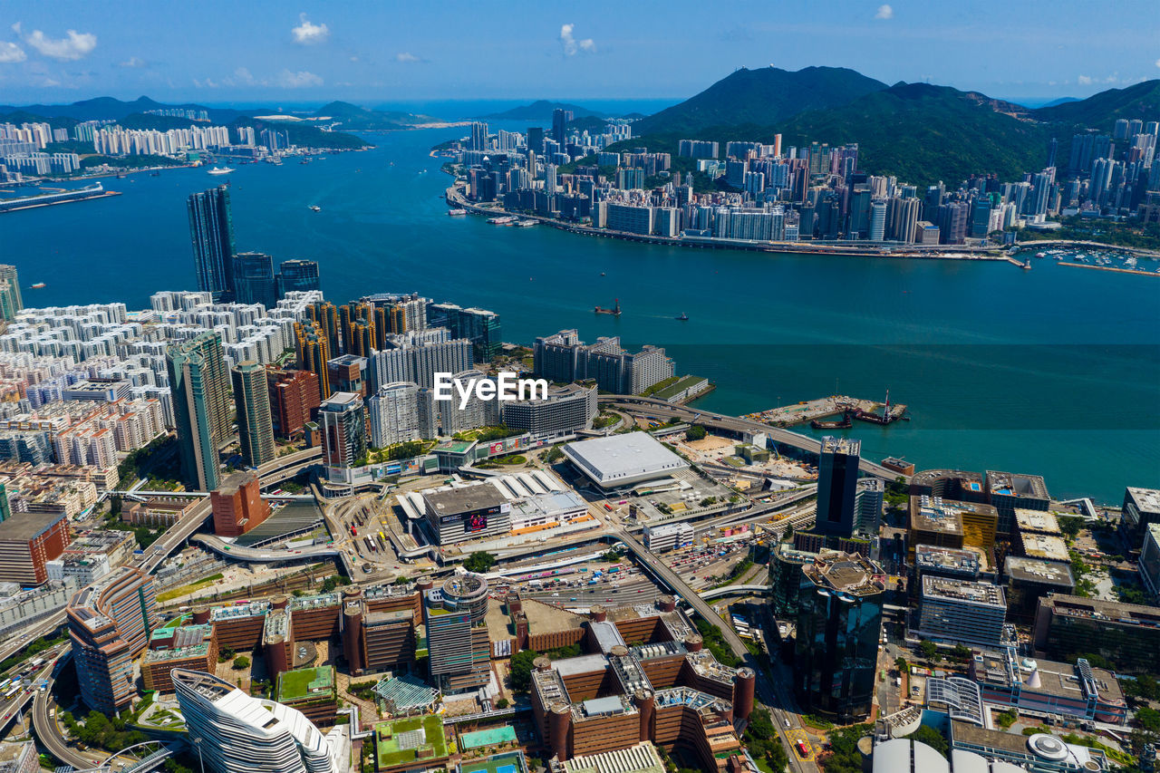 High angle view of city by sea and buildings against sky