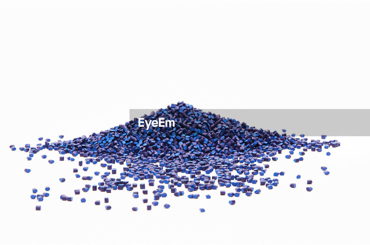 High angle view of blue plastic granules over white background