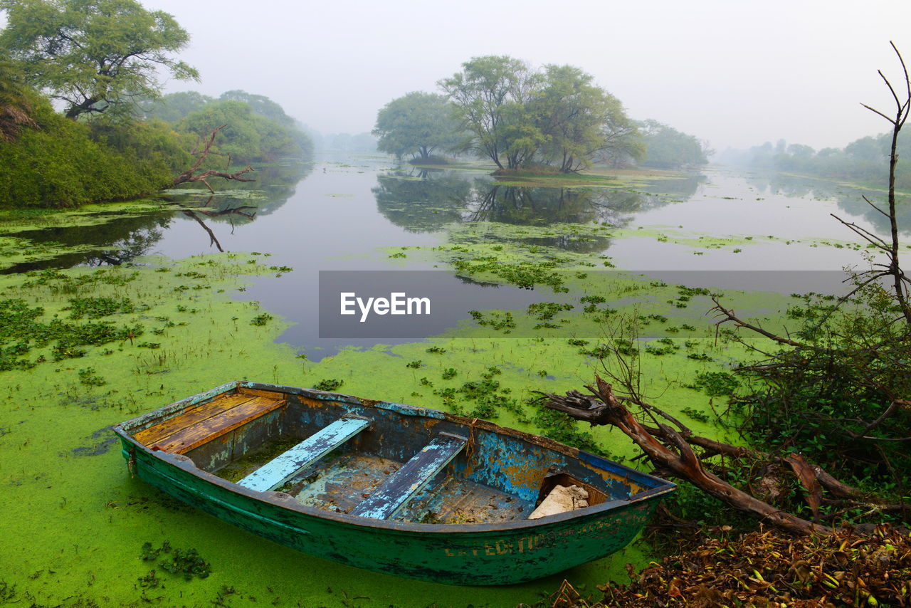 Abandoned boat moored in lake against sky