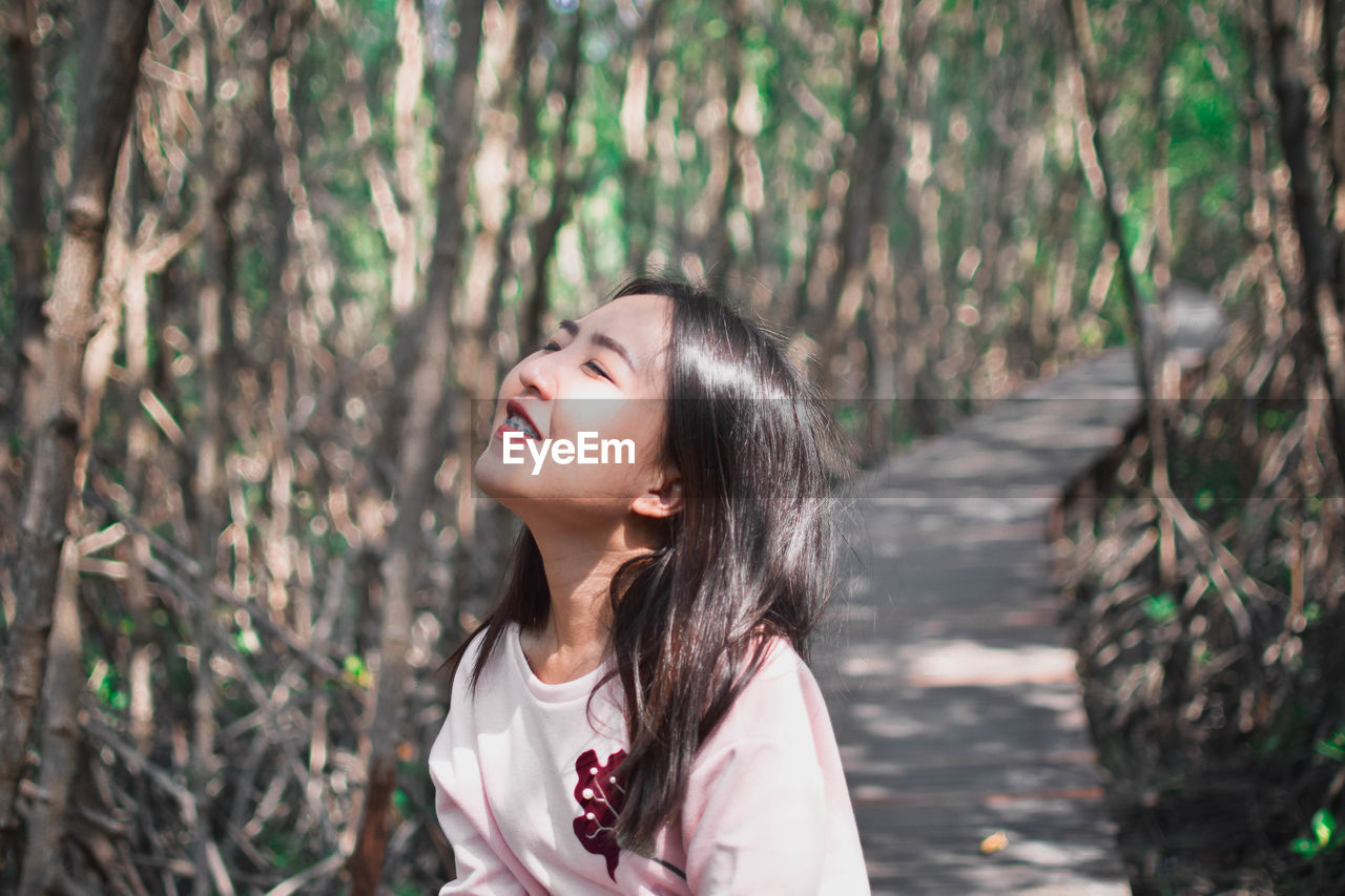 Beautiful woman with eyes closed standing in forest