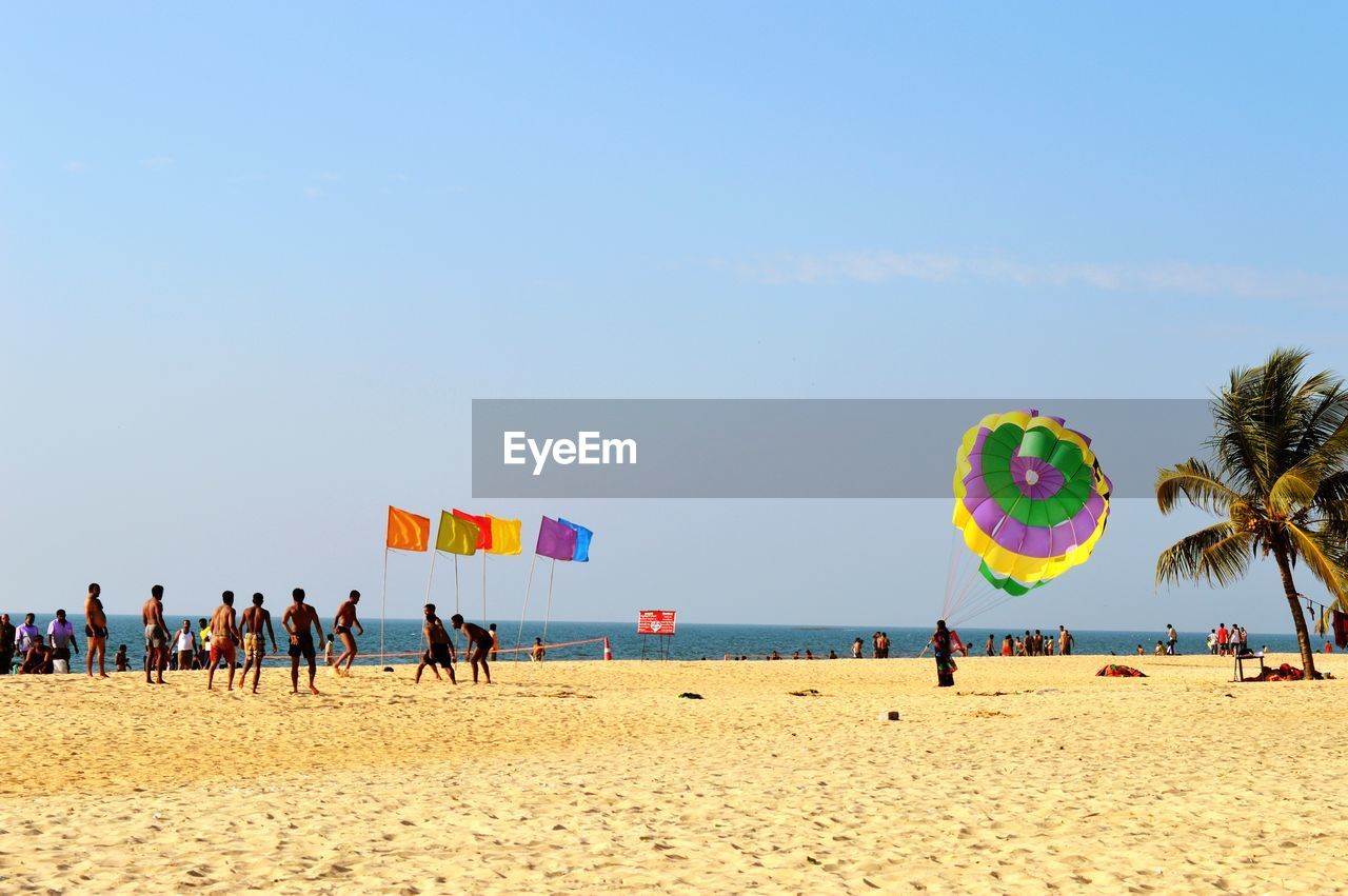 People at sandy beach against sky