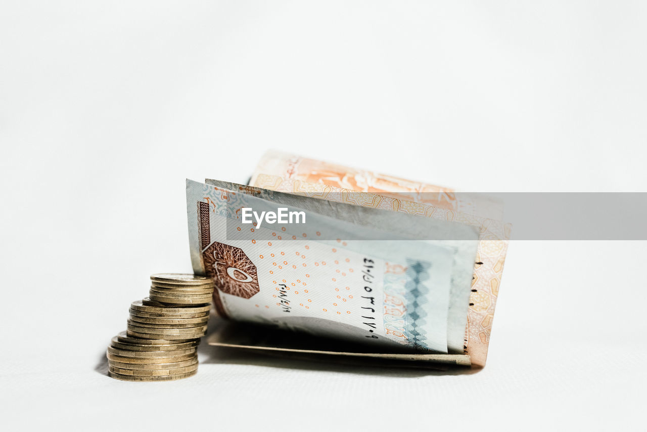 Close-up of coins with paper currencies against white background