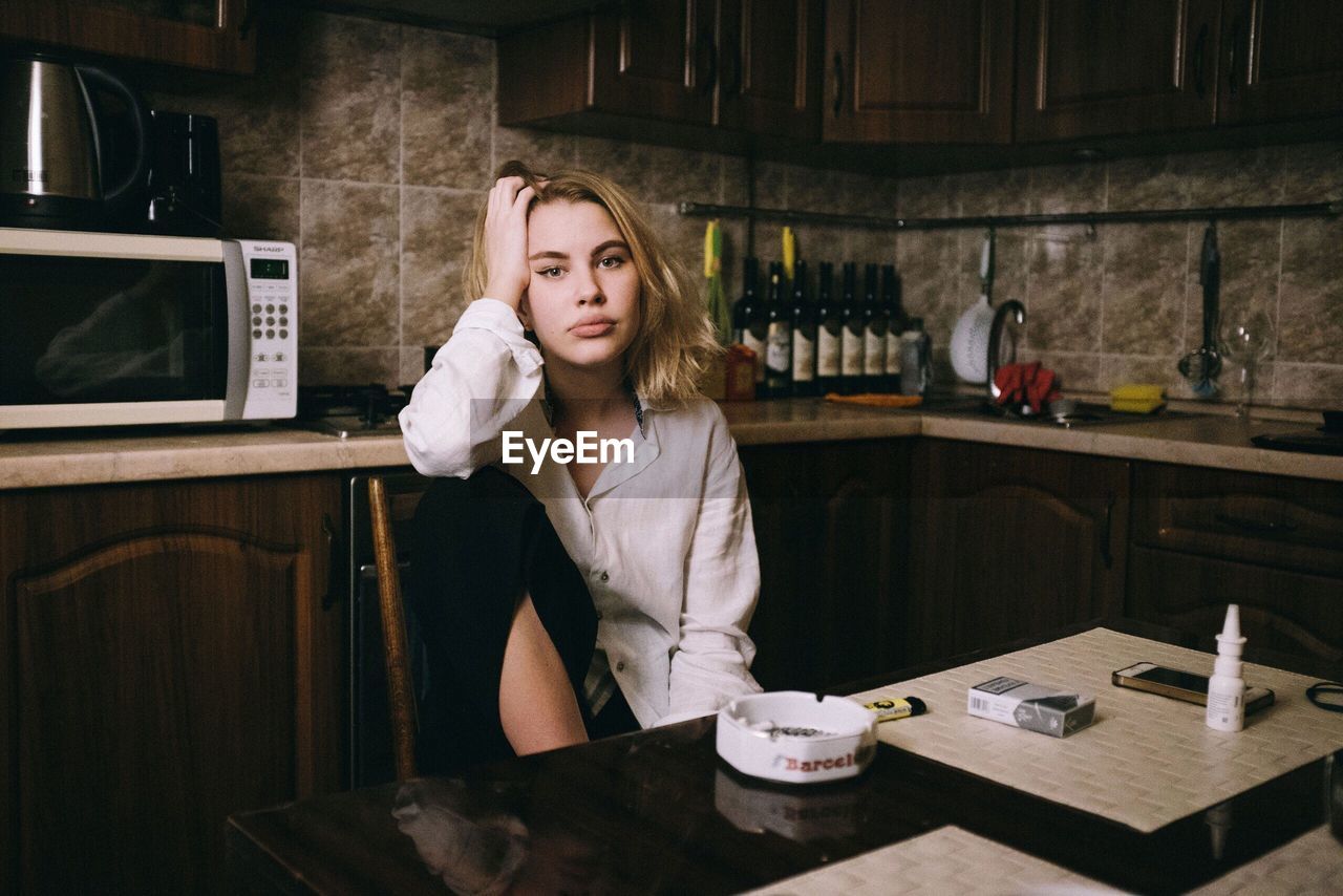 PORTRAIT OF WOMAN WITH COFFEE CUP ON TABLE AT HOME