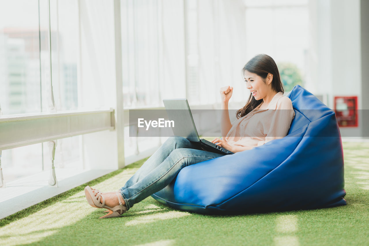 Businesswoman using laptop while sitting on bean bag on office