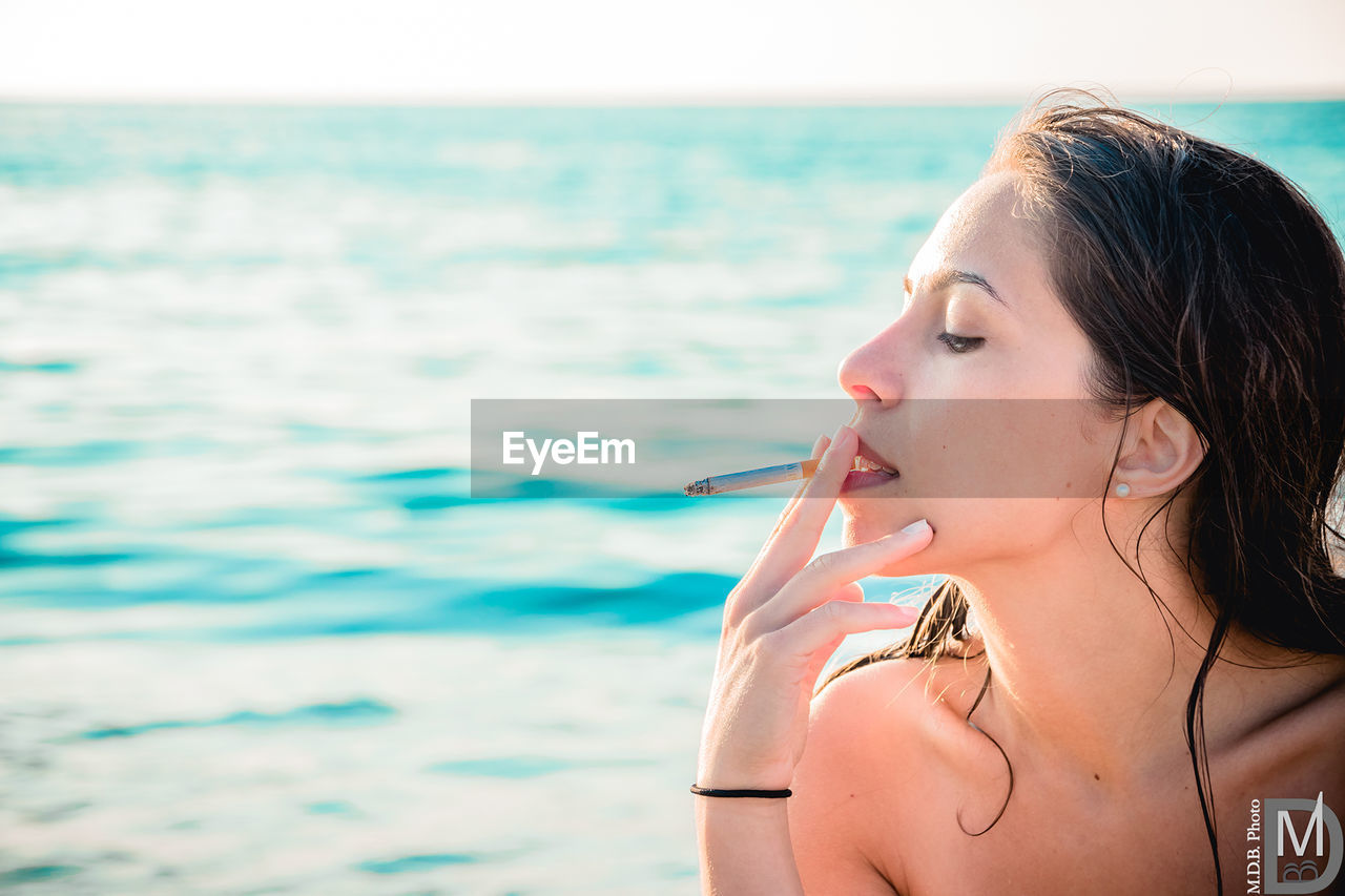 PORTRAIT OF BEAUTIFUL YOUNG WOMAN AT BEACH