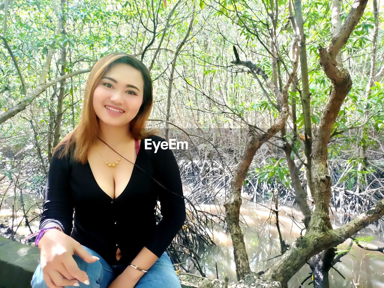 PORTRAIT OF SMILING YOUNG WOMAN IN FOREST