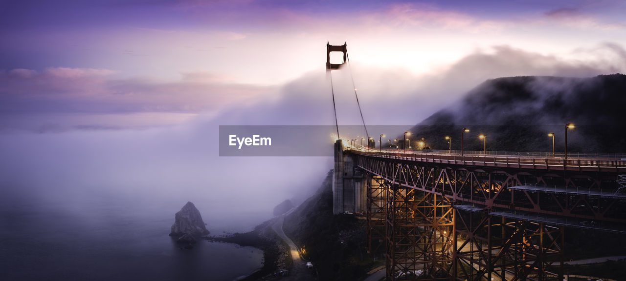 ILLUMINATED SUSPENSION BRIDGE AGAINST SKY DURING NIGHT