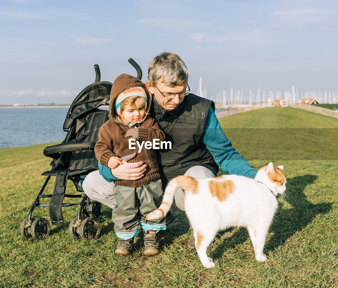 Full length of grandfather and daughter with cat on grass