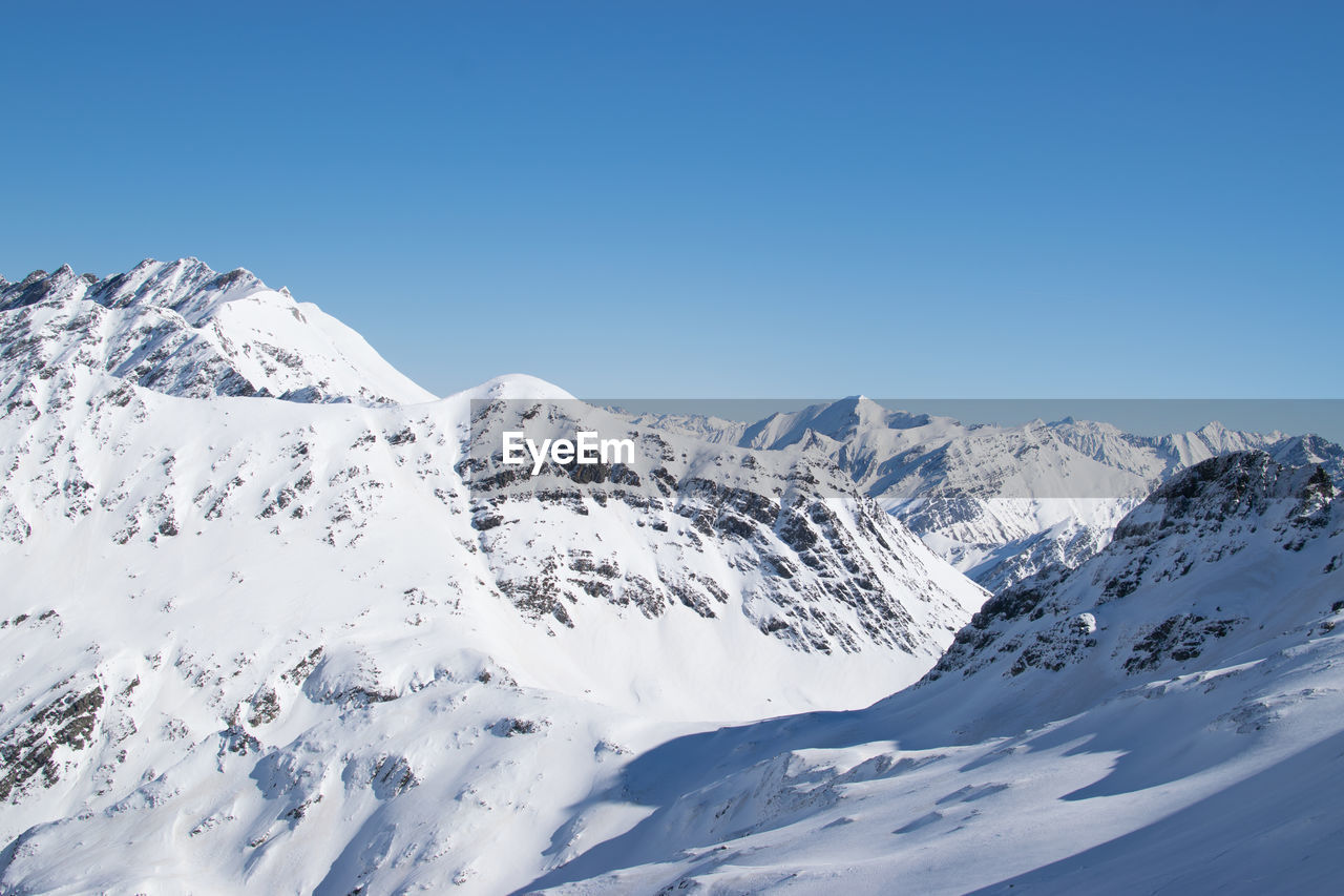 SCENIC VIEW OF SNOWCAPPED MOUNTAINS AGAINST BLUE SKY