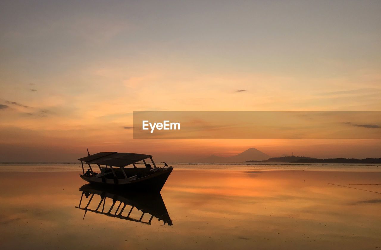 Boat at beach against sky during sunset