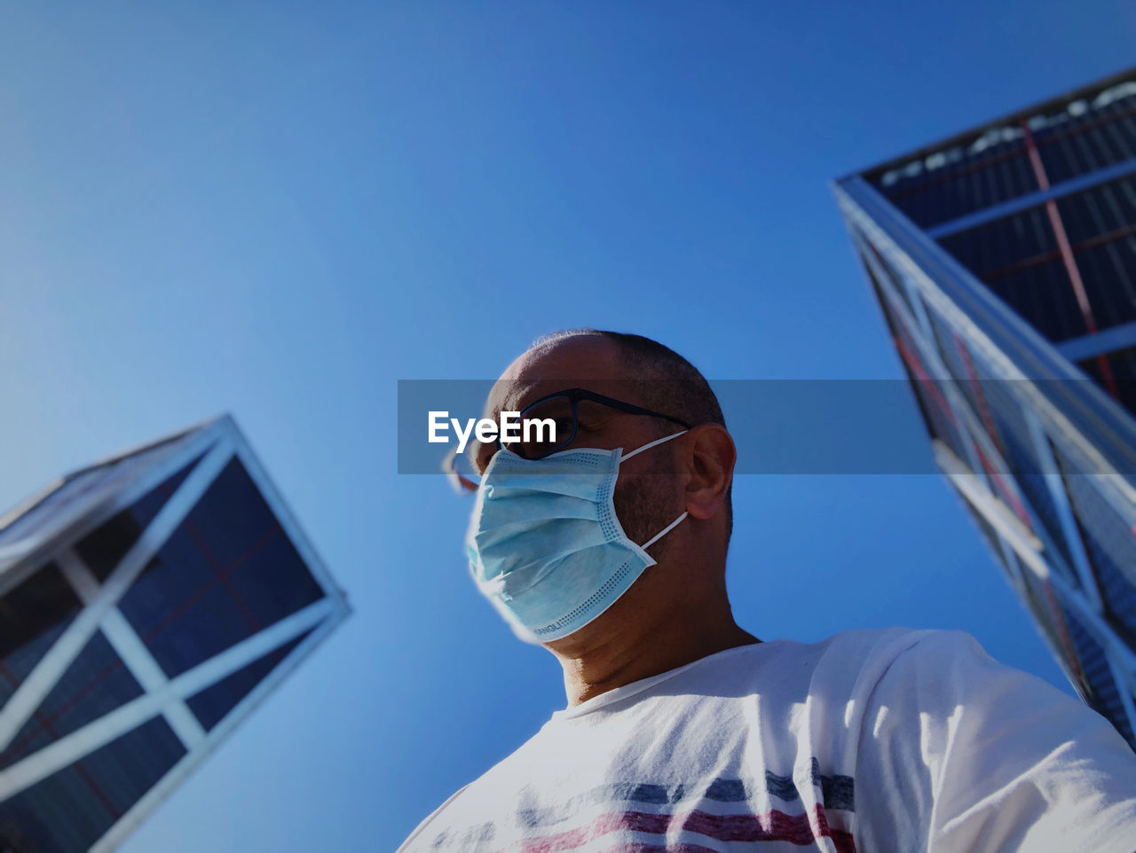 Low angle portrait of man against clear blue sky