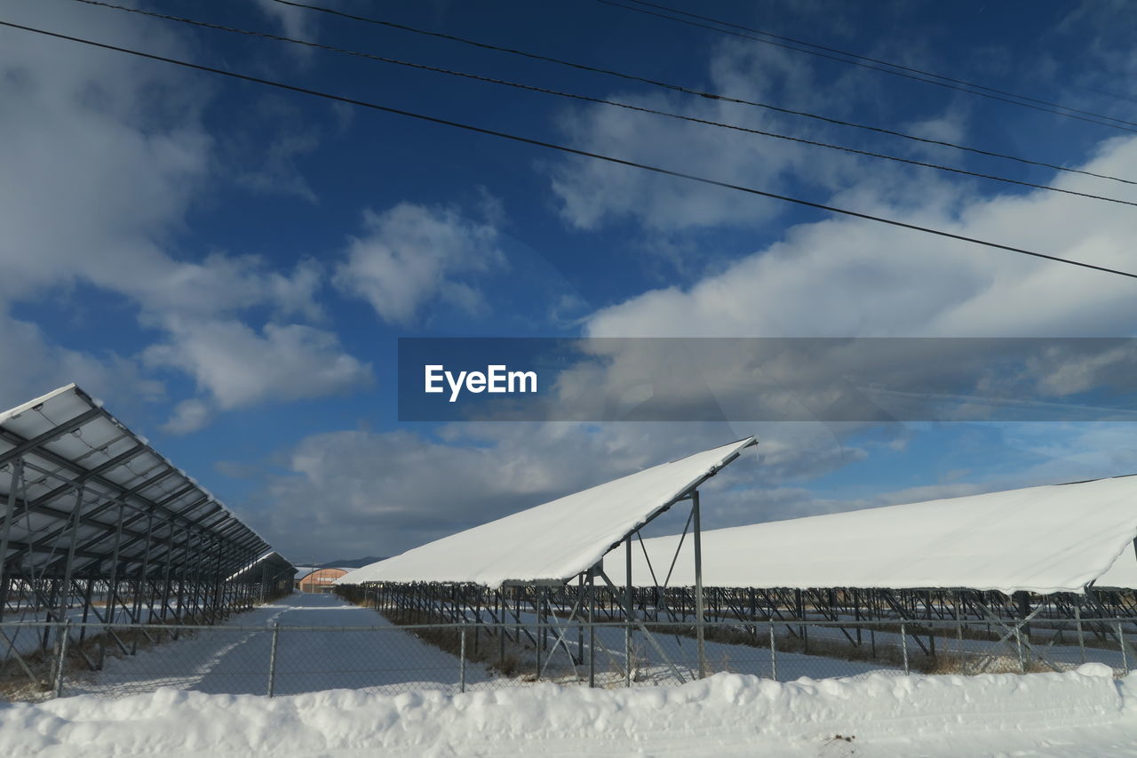 LOW ANGLE VIEW OF SNOW ON BRIDGE AGAINST SKY