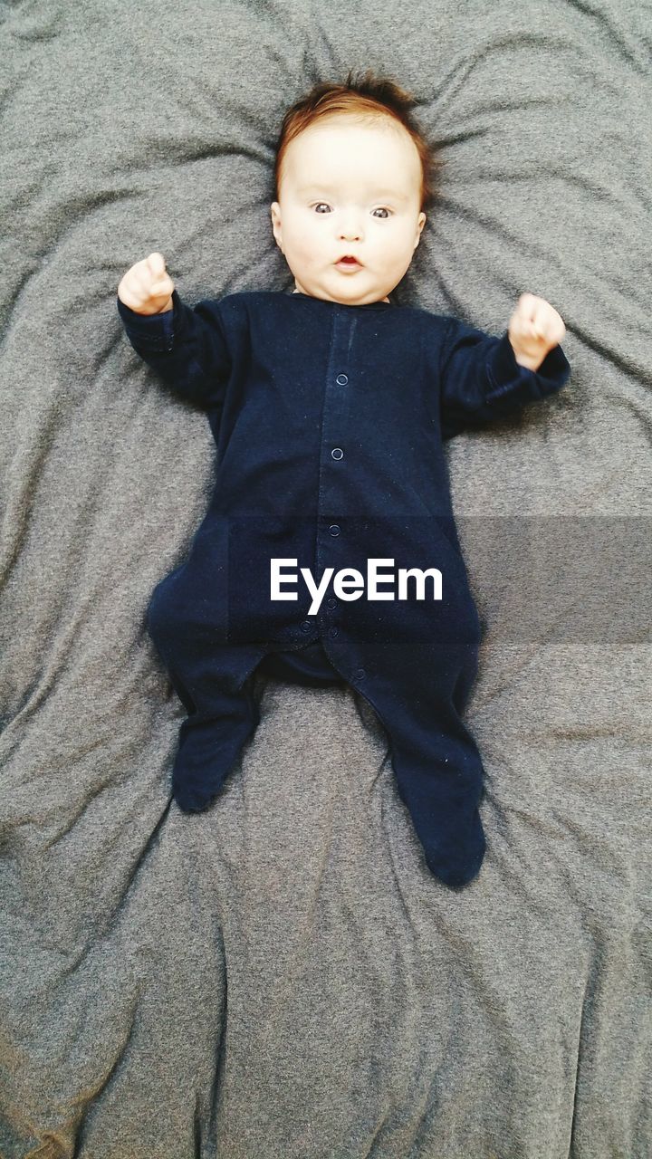 High angle portrait of cute baby lying on bed