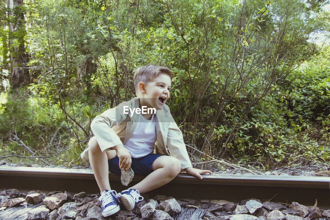 Happy boy sitting on railroad track