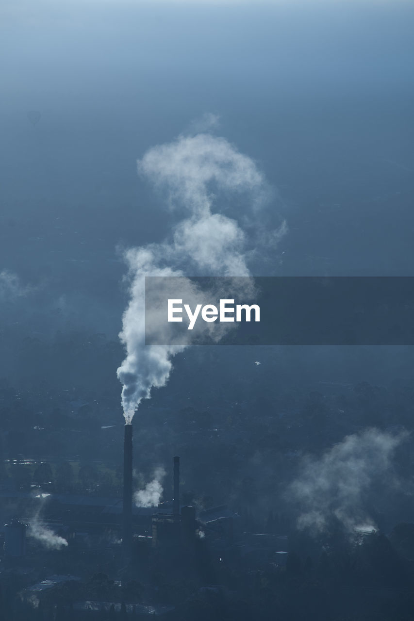 High angle view of smoke emitting chimneys during foggy weather