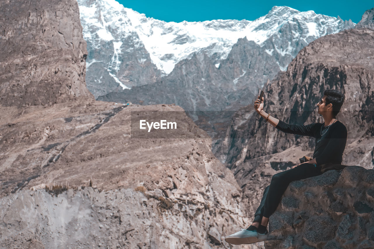 Man taking selfie while sitting on mountain