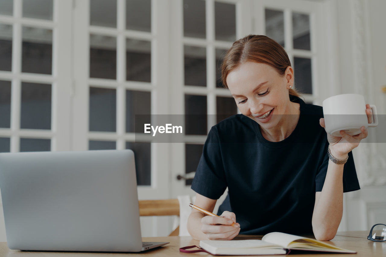 portrait of young woman using mobile phone while sitting at office
