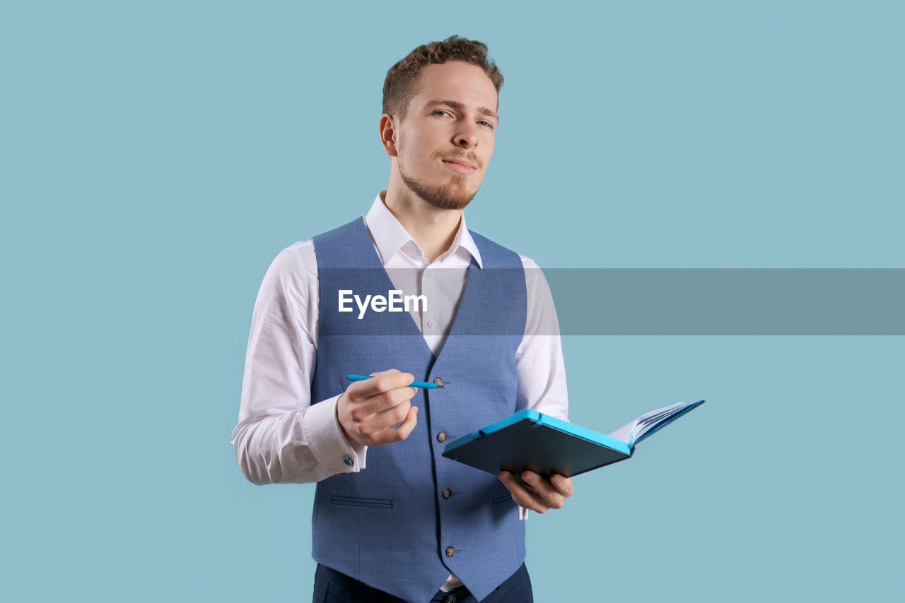 Portrait positive handsome young business assistant with a beard standing