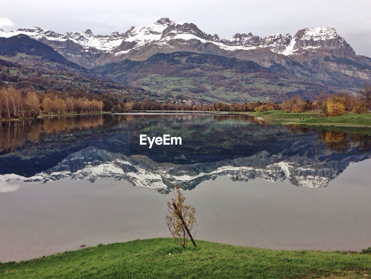 Refection of snow mountains on calm lake against sky