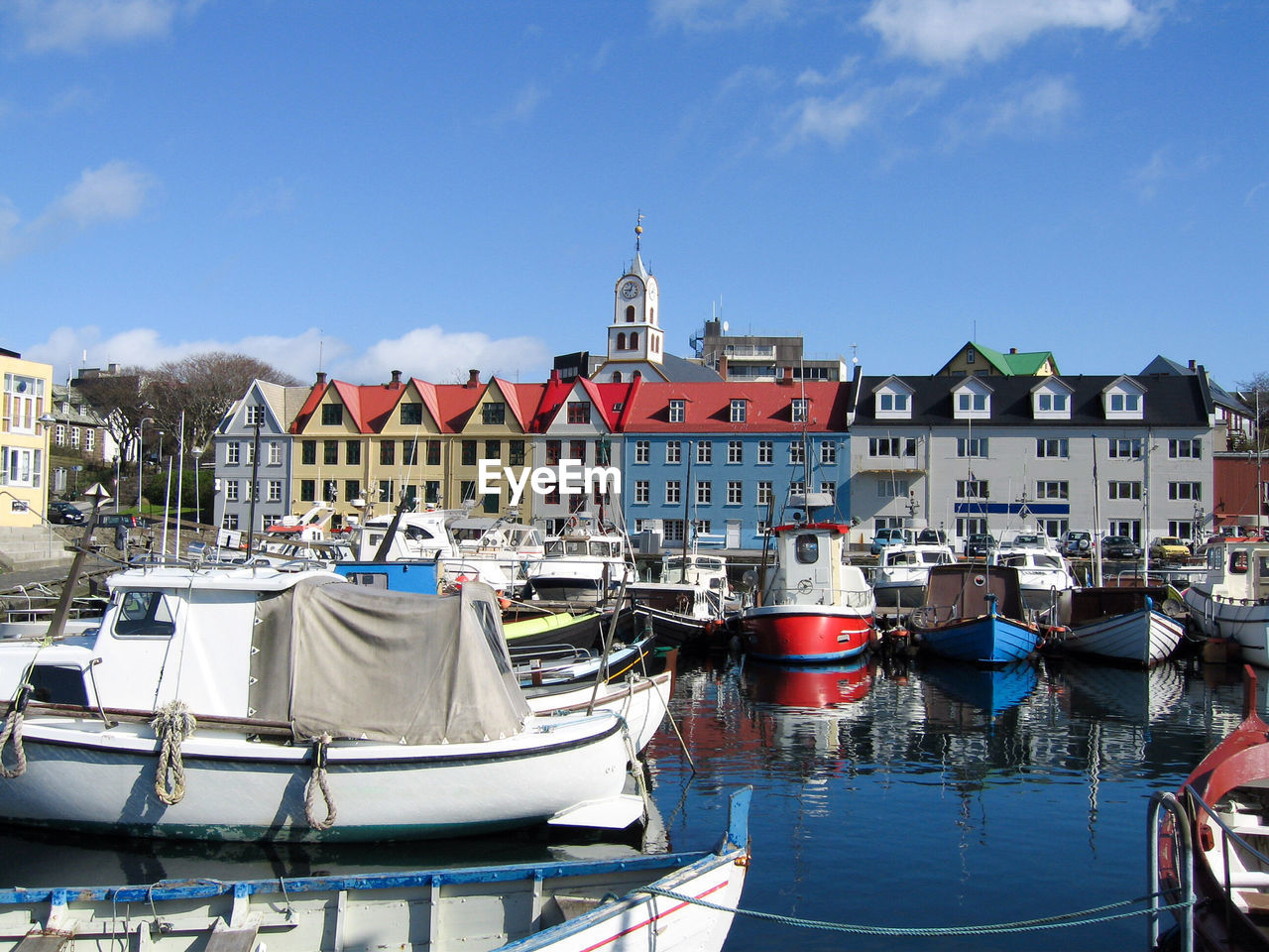 Sailboats moored at harbor against buildings in city