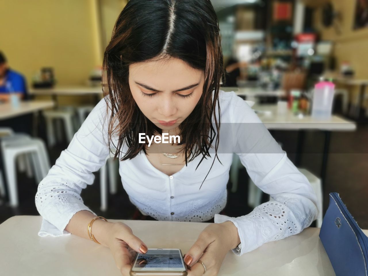 Young woman using phone on table