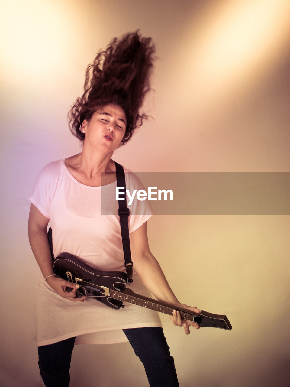 Woman playing guitar against colored background