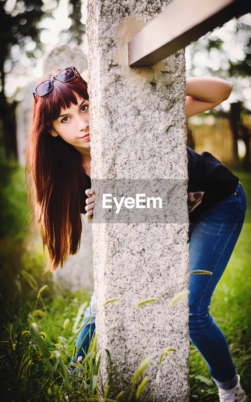 PORTRAIT OF WOMAN STANDING AGAINST TREE TRUNK