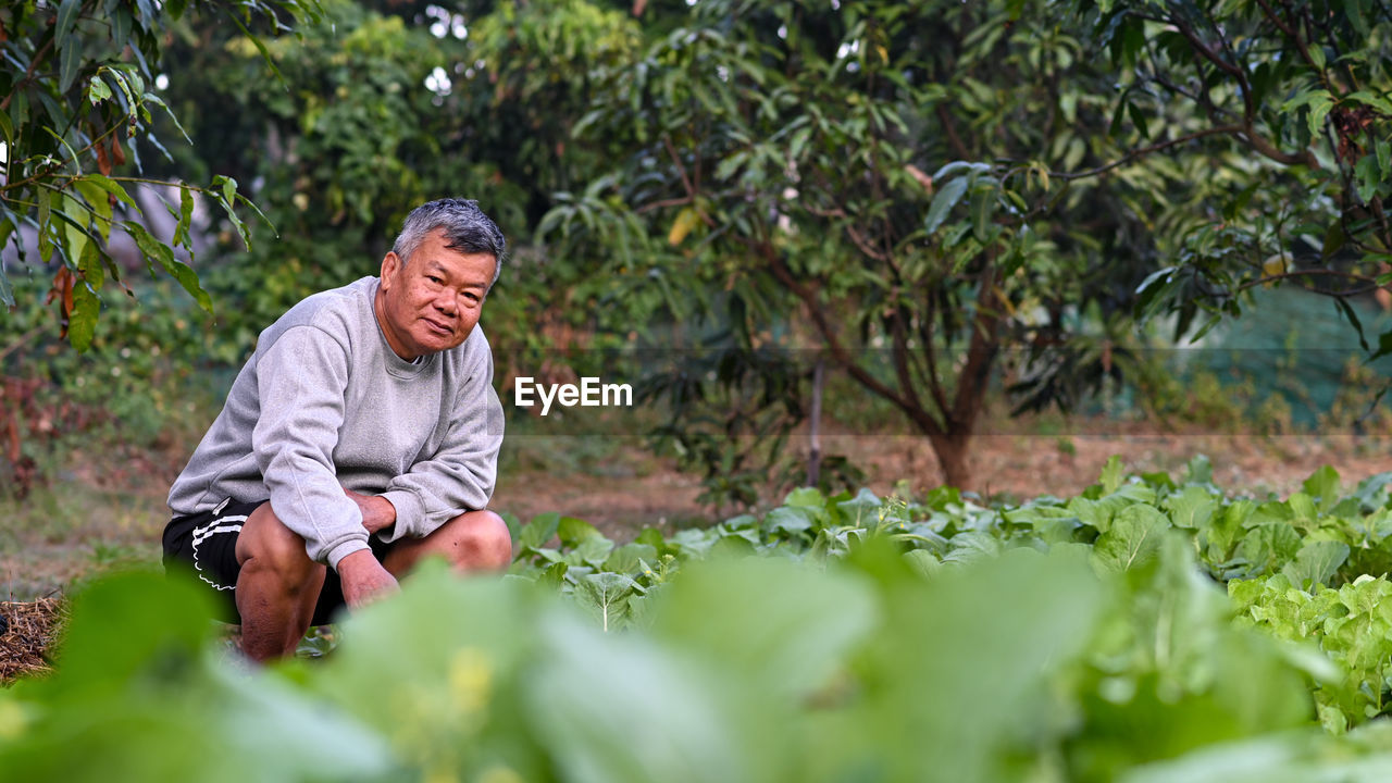 A senior farmer looks proudly at the camera in the vegetable field.