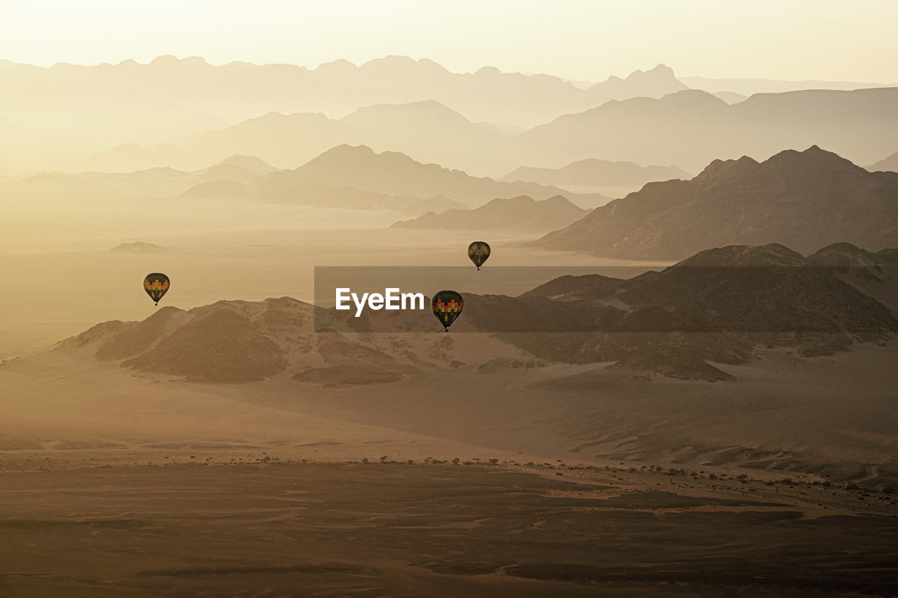 Hot air balloons flying over mountains during sunset