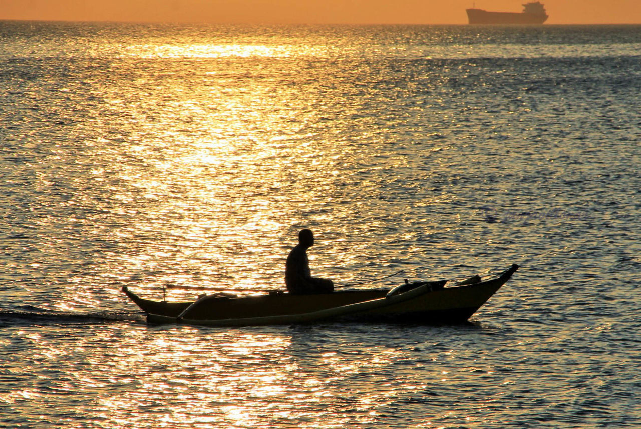 SILHOUETTE MAN IN BOAT AT SEA