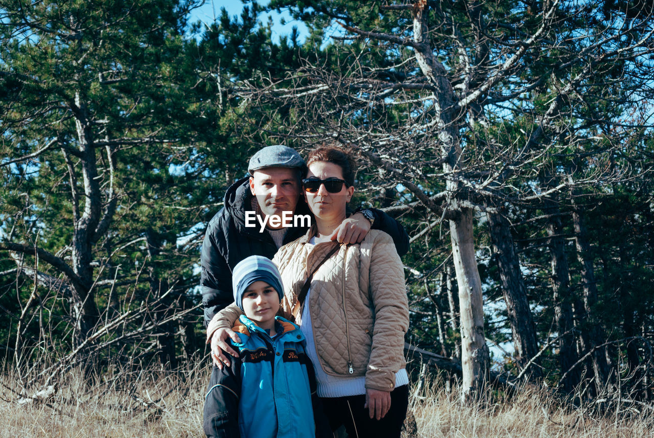 Portrait of family standing against trees at forest