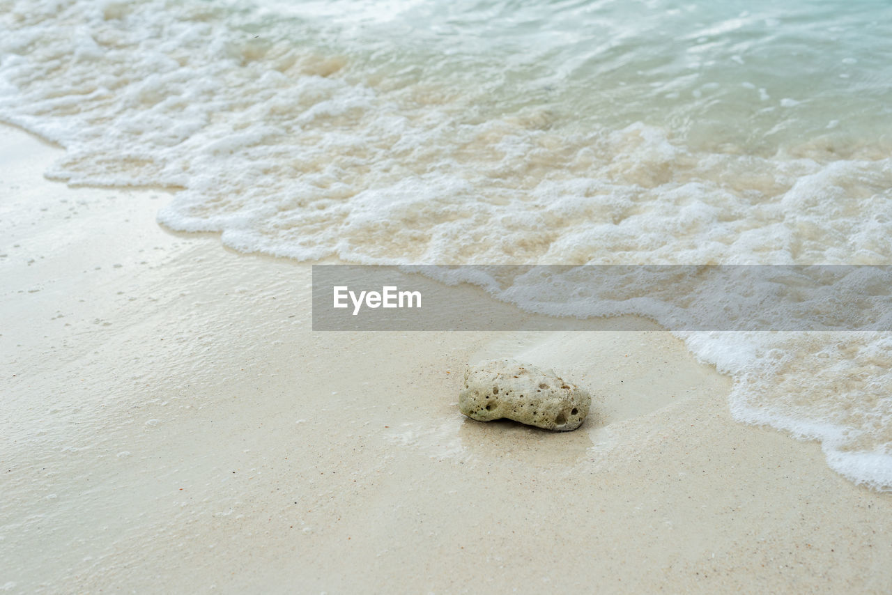 HIGH ANGLE VIEW OF SURF ON SAND