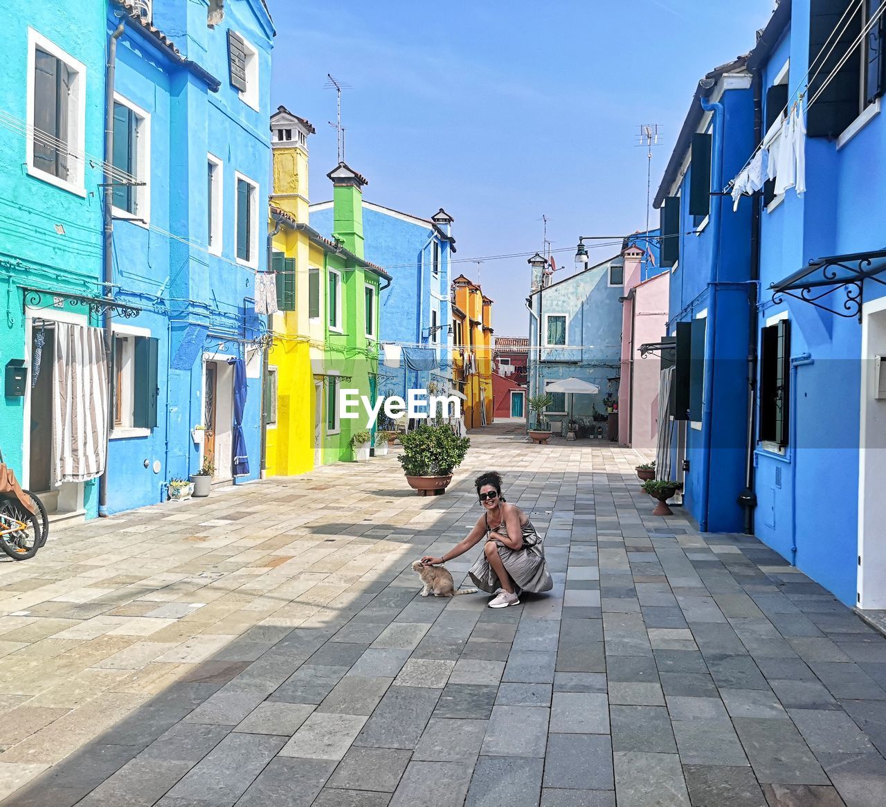 Woman with cat crouching on road in city