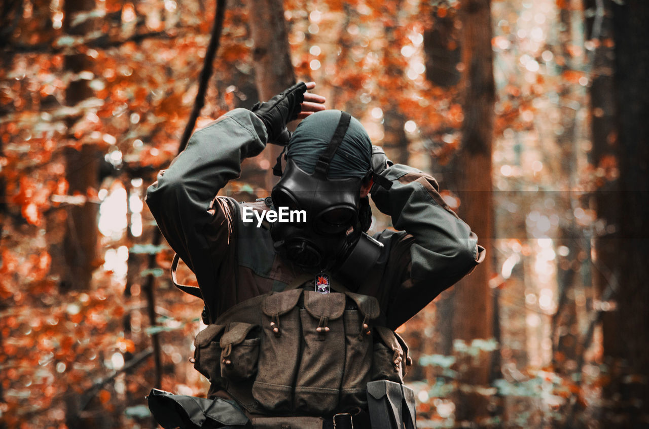 REAR VIEW OF A MAN PHOTOGRAPHING IN FOREST