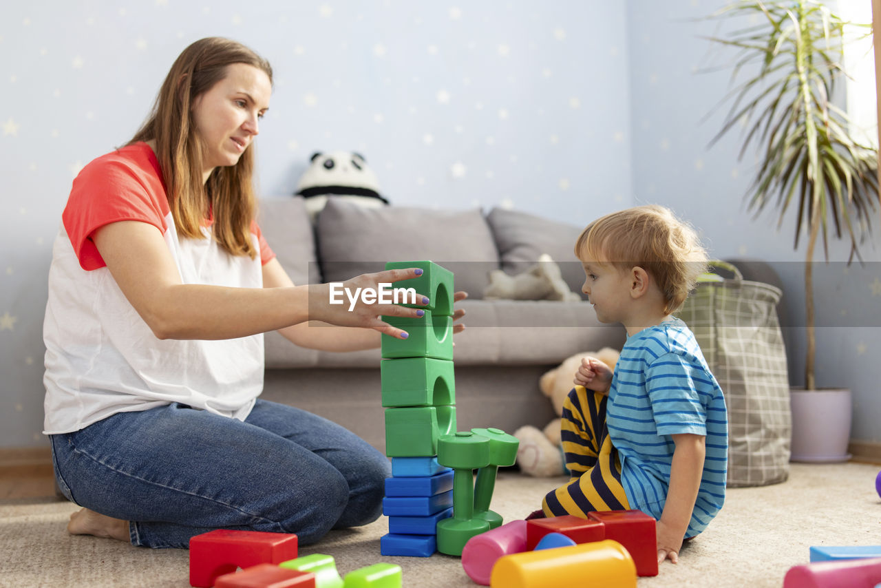 side view of mother and daughter sitting on floor