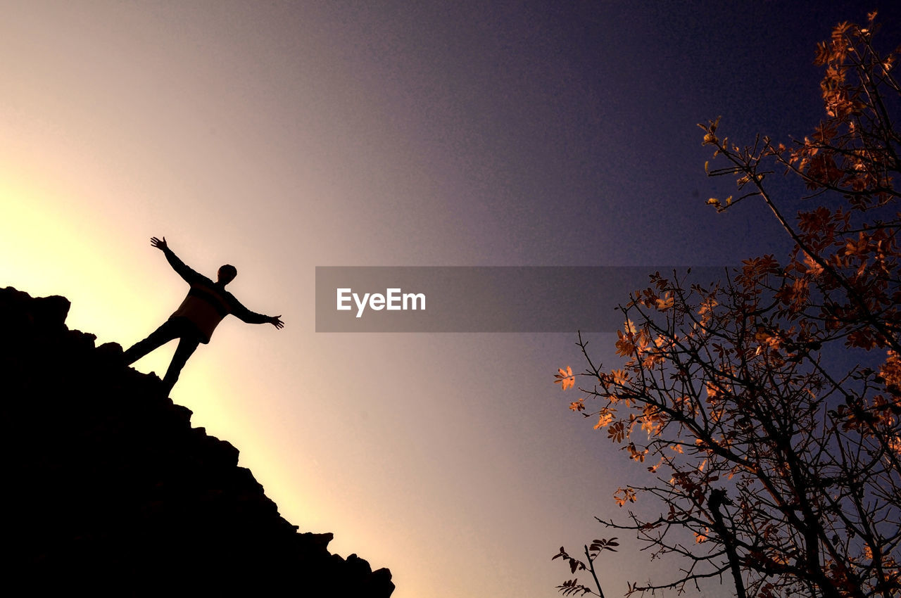 LOW ANGLE VIEW OF SILHOUETTE PERSON AGAINST SKY