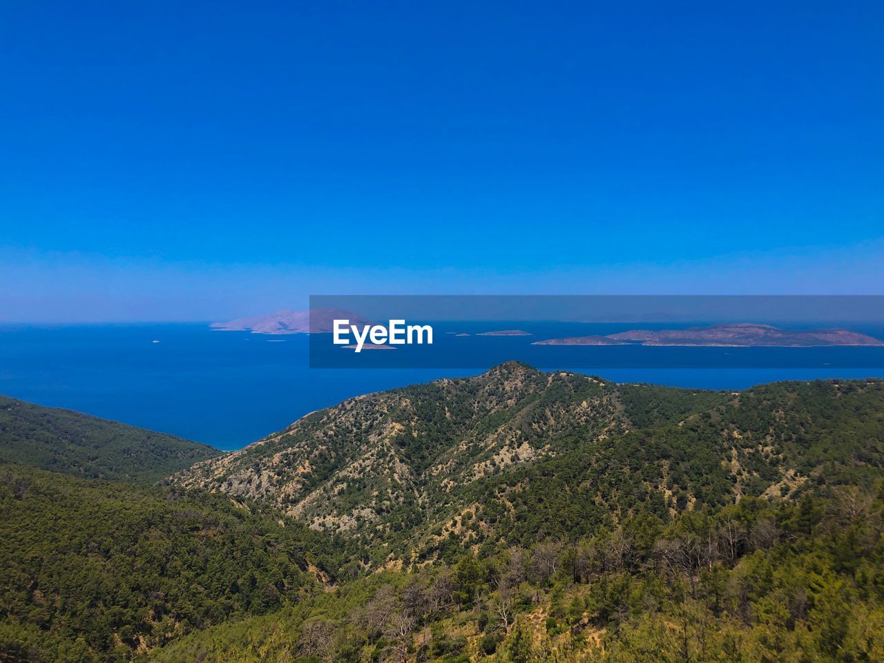 Scenic view of sea and mountains against blue sky