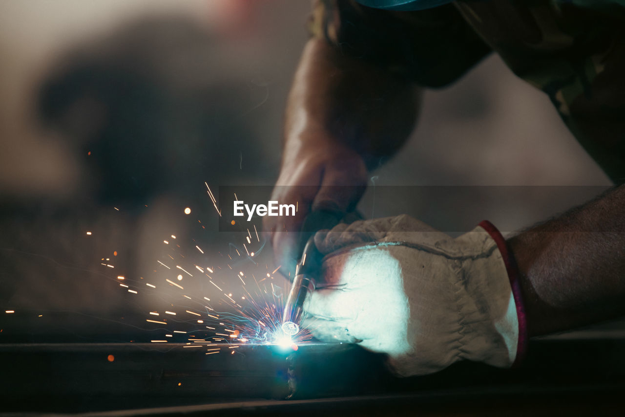 Cropped hands of welder working at factory