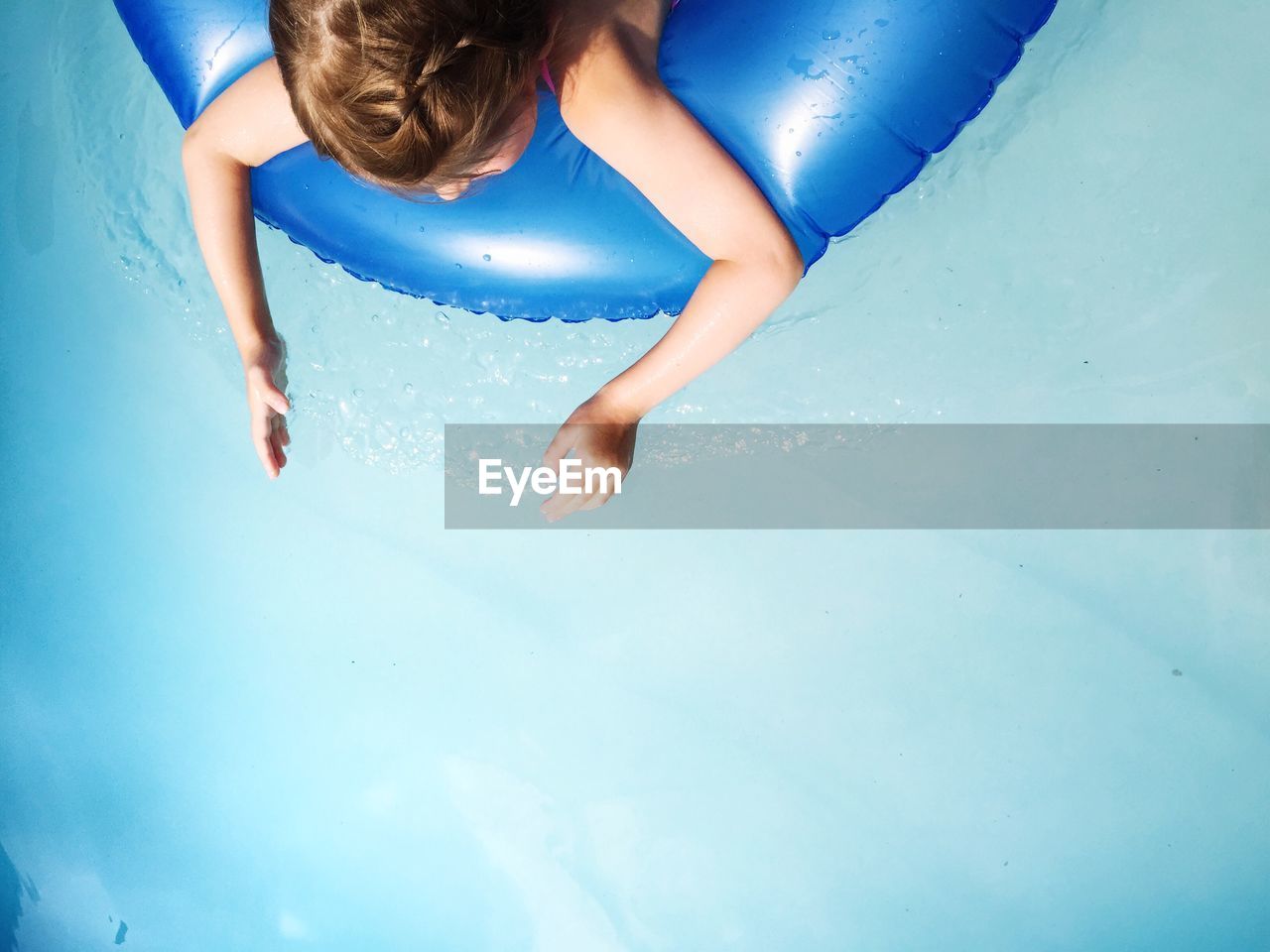 High angle view of girl relaxing on inflatable ring in swimming pool
