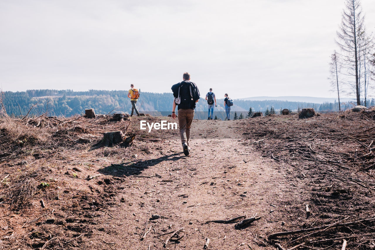 REAR VIEW OF PEOPLE WALKING ON ROAD