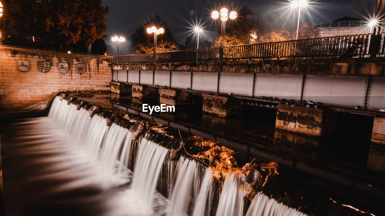 Illuminated street lights by river at night