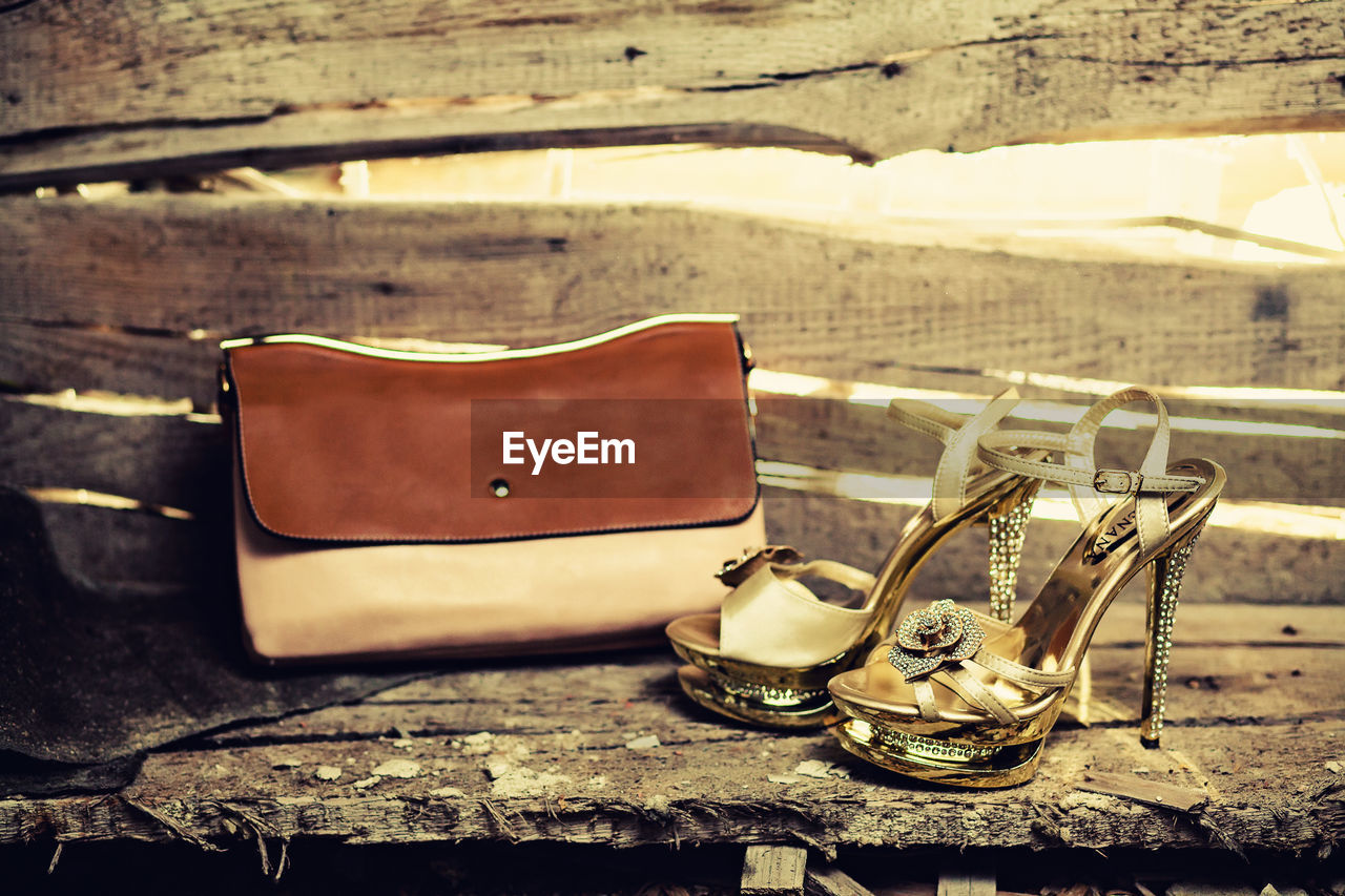 Close-up of shoes and bag by wooden wall