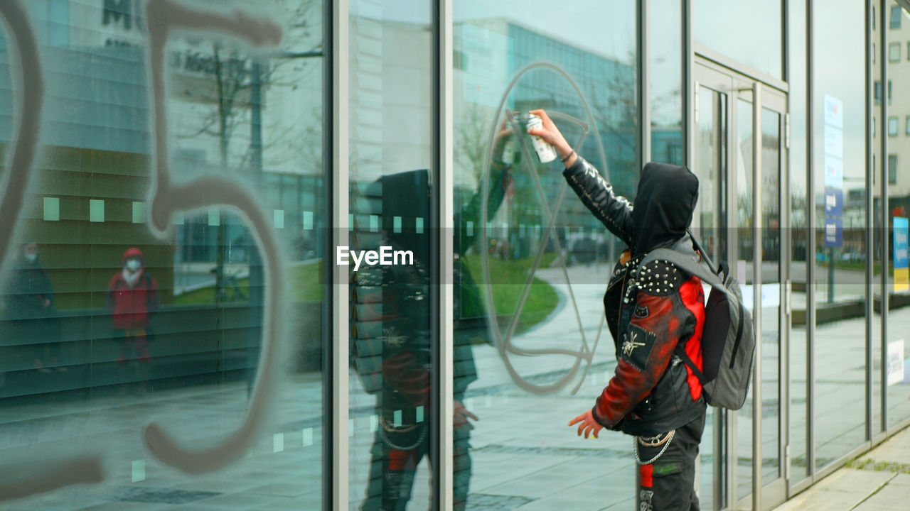 REFLECTION OF WOMAN ON GLASS WINDOW IN CITY