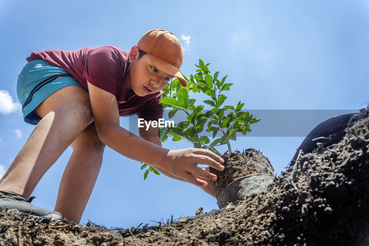 Low angle view of boy doing gardening outdoors