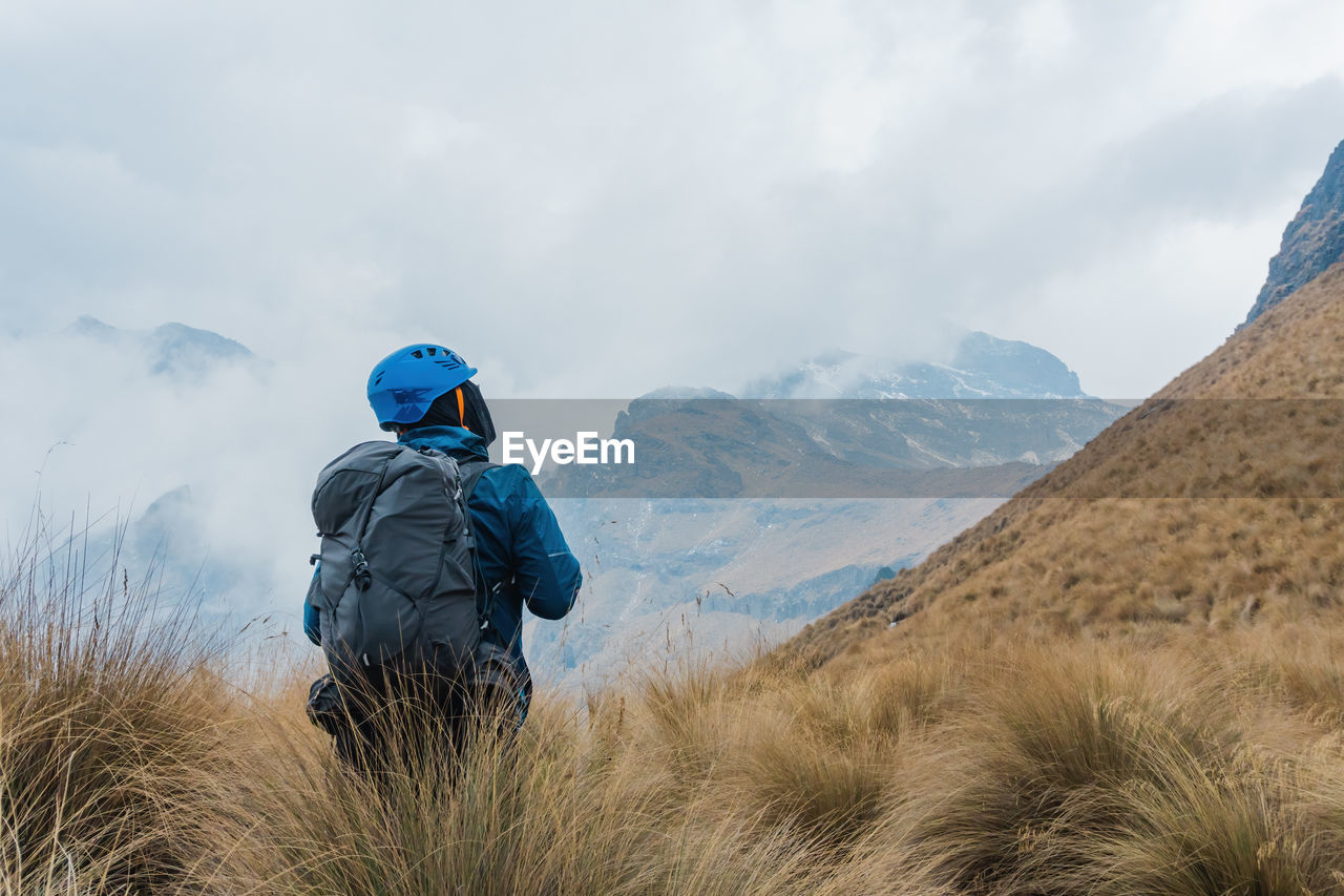 Rear view of man standing on mountain against sky